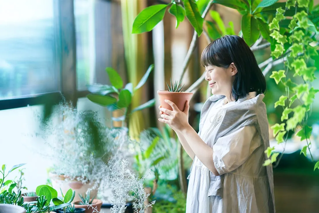 植物を手に微笑む女性